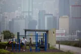 Picture of a park with people exercising and a Chinese skyline in the background.